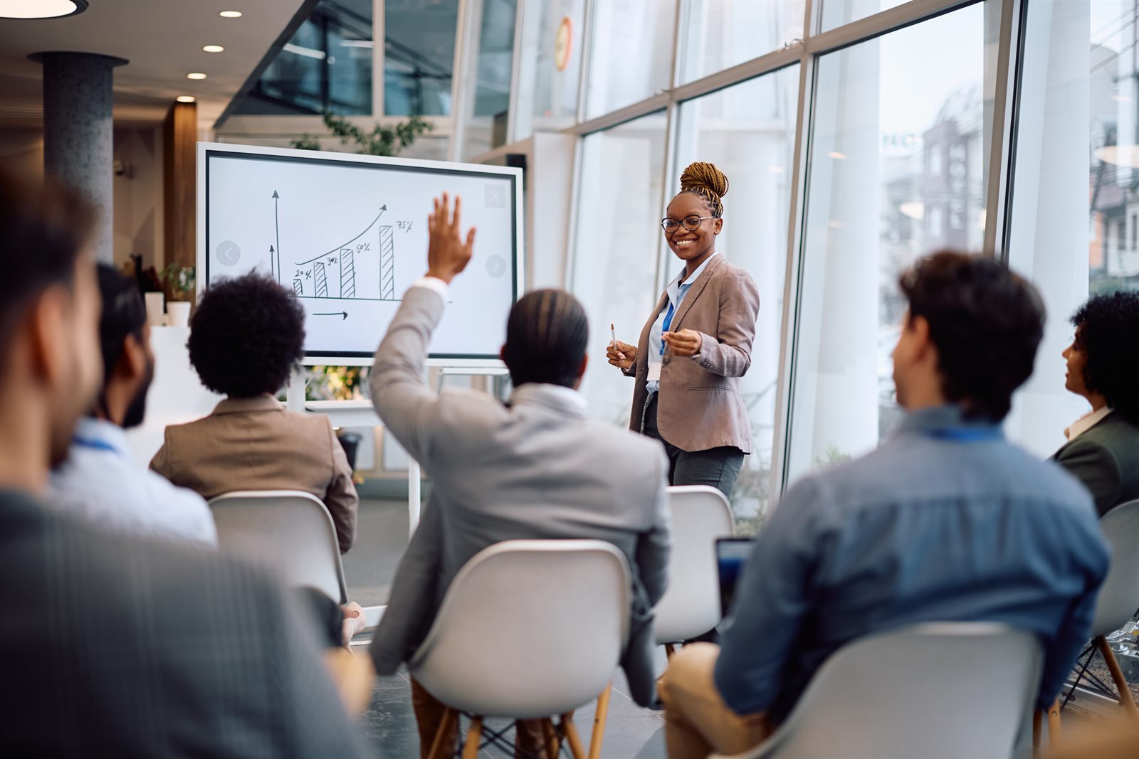 Trainer leading a workplace session as an attendee raises a hand