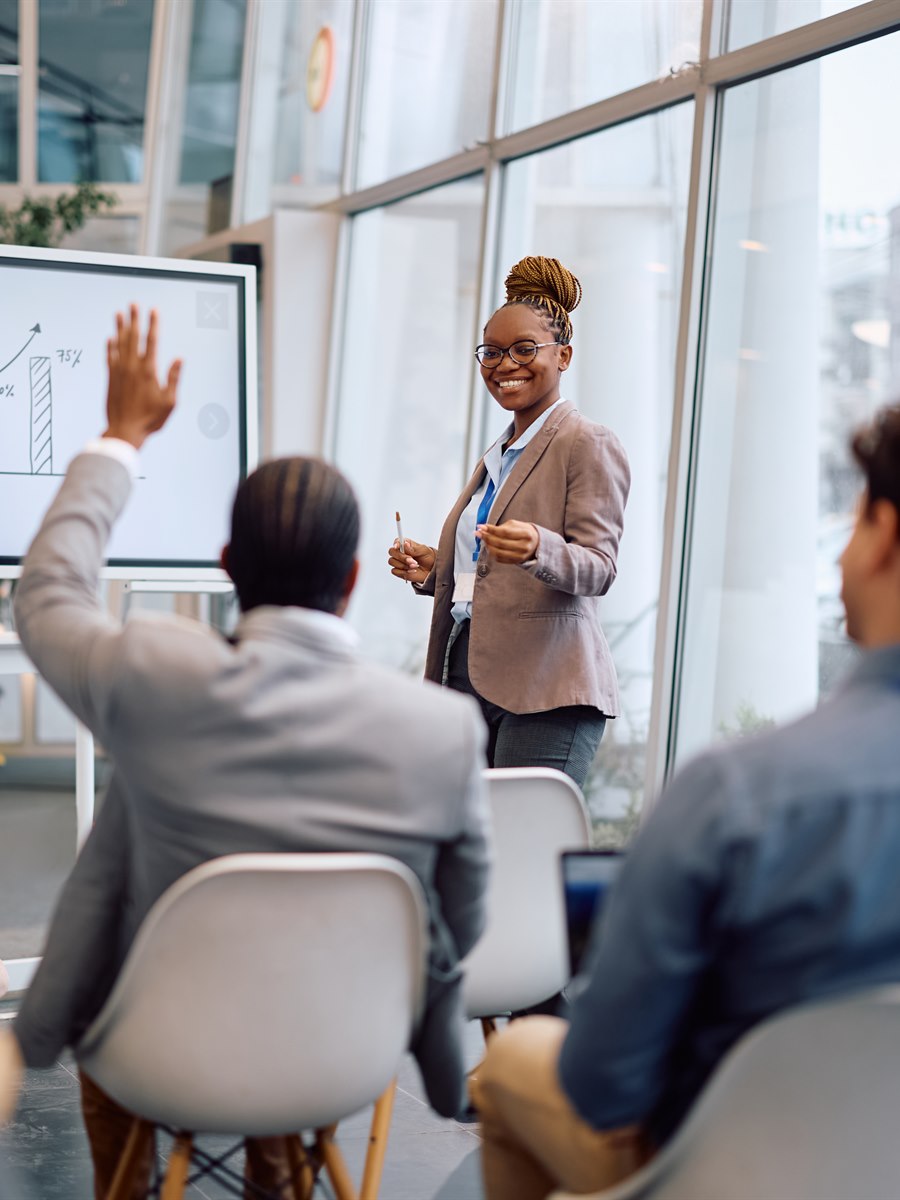 Trainer leading a workplace session as an attendee raises a hand